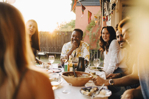 Fröhliche Freunde unterhalten sich beim Abendessen am Esstisch in einer Party - MASF12661