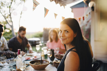 Portrait of smiling woman enjoying dinner party with friends at back yard - MASF12663