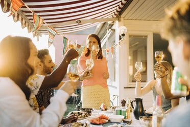 Multi-ethnic friends raising toast while enjoying in dinner party at yard - MASF12665