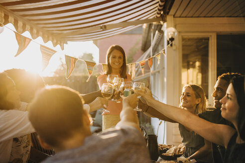 Fröhliche multiethnische Freunde stoßen mit Weingläsern an, während sie eine Dinnerparty genießen - MASF12667
