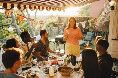 Frau stößt an, während sie das Essen mit Freunden bei einer Dinnerparty genießt - MASF12668