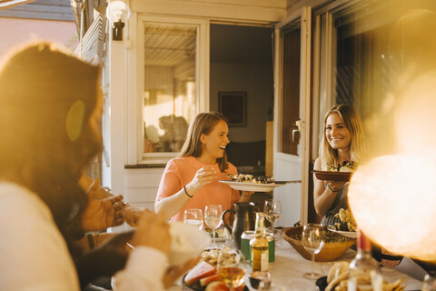 Glückliche Freunde genießen das Essen am Esstisch bei einer Dinnerparty, lizenzfreies Stockfoto