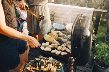 Midsection of female friends grilling food on barbecue grill at yard - MASF12676