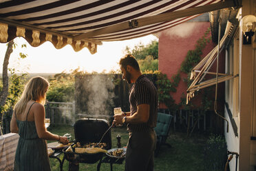 Männliche und weibliche Freunde grillen Essen und trinken Wein auf einer Party - MASF12678