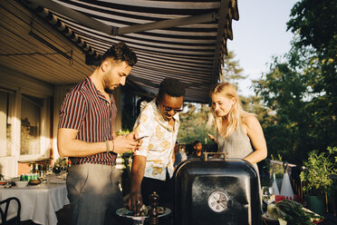 Freunde unterhalten sich bei gegrilltem Essen auf einer Dinnerparty im Hinterhof - MASF12682