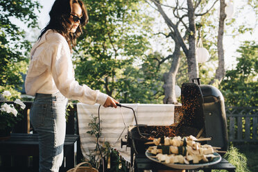 Frau, die im Sommer im Garten Essen auf dem Grill grillt - MASF12686