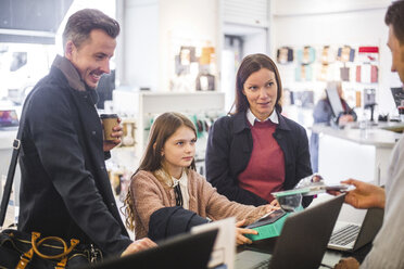 Verkäuferin, die einer Familie in einem Elektronikgeschäft Computergeräte zeigt - MASF12738