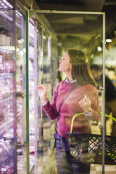 Reife Frau schaut in den Kühlschrank beim Einkaufen im Lebensmittelgeschäft - MASF12747