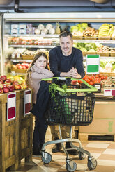 Porträt von Vater und Tochter in voller Länge beim Einkaufen im Supermarkt - MASF12754