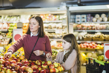 Mother and daughter choosing fresh apples at market stall - MASF12756