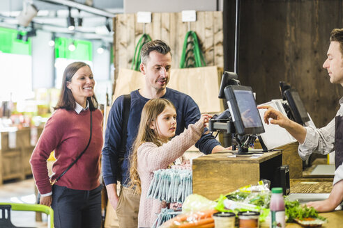 Nettes Mädchen tippt Pin-Code an der Kasse im Supermarkt von Familie - MASF12759