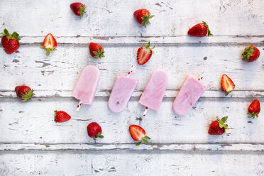 Hausgemachte Erdbeer-Joghurt-Eislutscher mit frischen Erdbeeren auf weißem Holz - LVF08067