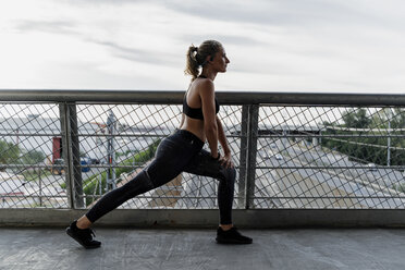 Sportliche Frau beim Aufwärmen auf einer Brücke - ERRF01470