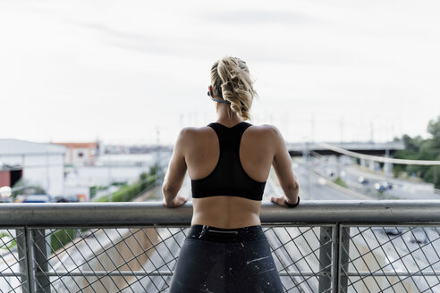 Sportliche Frau steht auf einer Brücke und betrachtet die Aussicht - ERRF01471