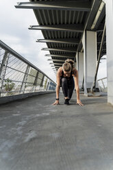Sporty woman in starting position on a bridge, starting to run - ERRF01483