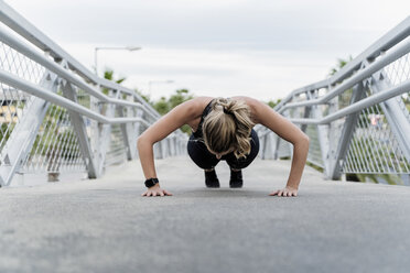 Sporty woman doing push ups, working out on a bridge - ERRF01486