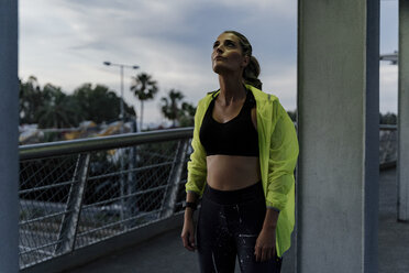 Sportliche Frau, die auf einer Brücke steht und nach oben schaut - ERRF01503