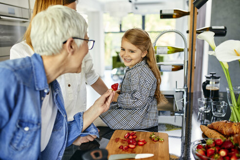 Großmutter bietet ihrer Enkelin Erdbeeren an, Mutter schaut zu - ZEDF02322