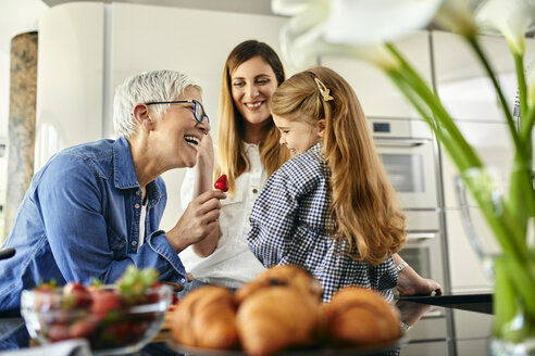 Großmutter bietet ihrer Enkelin Erdbeeren an, Mutter schaut zu - ZEDF02323