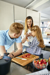 Happy family eating fresh strawberries in modern kitchen - ZEDF02327