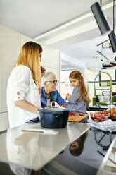 Mother, daughter and grandmother having fun, chopping strawberries in the kitchen - ZEDF02333