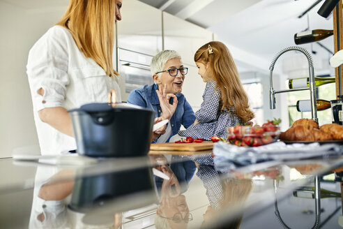 Mutter, Tochter und Großmutter haben Spaß beim Schneiden von Erdbeeren in der Küche - ZEDF02334