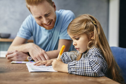 Vater und Tochter sitzen am Tisch und malen ein Malbuch - ZEDF02357