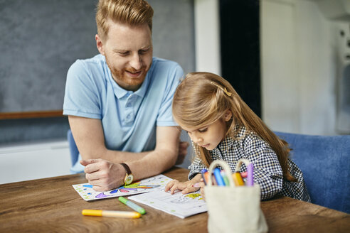 Vater und Tochter sitzen am Tisch und malen ein Malbuch - ZEDF02359