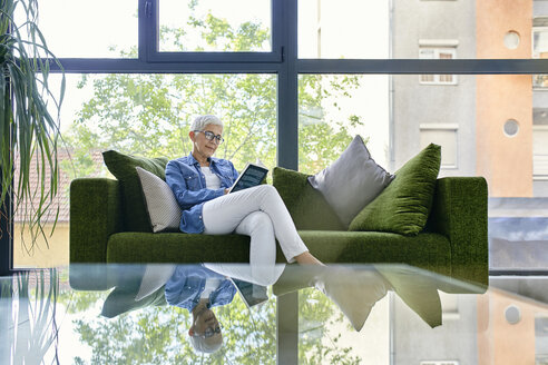 Ältere Frau sitzt auf der Couch und liest ein Buch - ZEDF02363