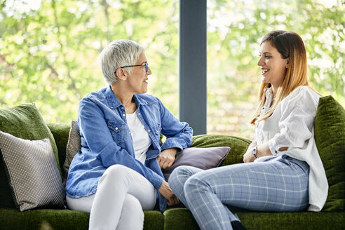 Mutter und erwachsene Tochter sitzen auf der Couch und unterhalten sich - ZEDF02373