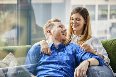 Glückliches Paar auf der Couch sitzend, die Arme umeinander gelegt - ZEDF02377