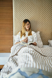 Woman sitting in bed, reading a book - ZEDF02395