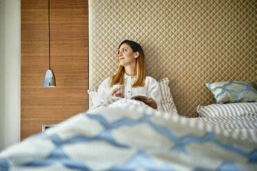 Woman sitting in bed, reading a book - ZEDF02397