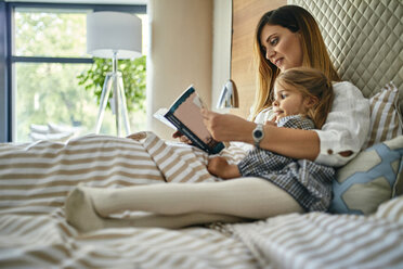 Mother and daughhter reading a book in bed - ZEDF02398
