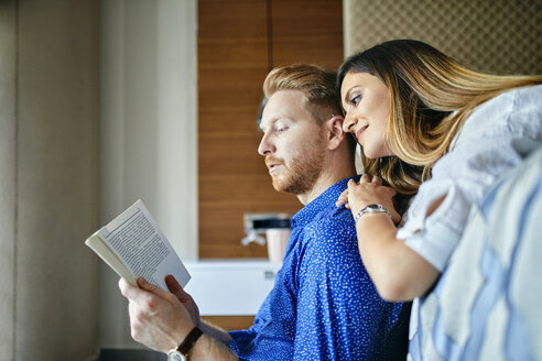 Zärtliches Paar liest gemeinsam ein Buch im Schlafzimmer - ZEDF02400