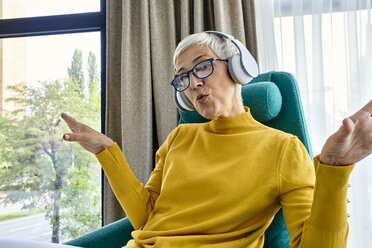 Ältere Frau sitzt im Sessel und hört Musik mit Kopfhörern - ZEDF02408