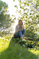 Young redheaded woman using smartphone in a park - AFVF03167