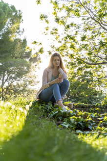 Junge rothaarige Frau benutzt Smartphone in einem Park - AFVF03167