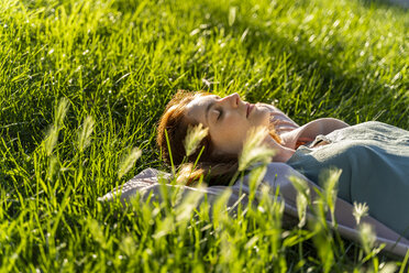 Young redheaded woman lying on meadow in a park - AFVF03172