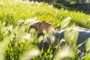 Young redheaded woman lying on meadow in a park - AFVF03173