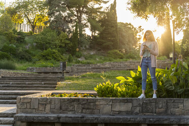 Young redheaded woman using smartphone in a park - AFVF03186