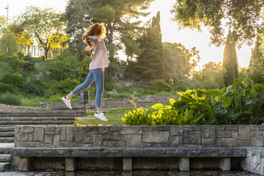 Young redheaded woman jumping in a park - AFVF03187