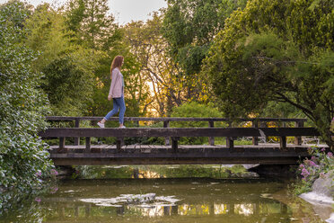 Junge rothaarige Frau balanciert auf einer Brücke in einem Park - AFVF03209