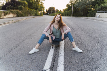 Young woman sitting on skateboard - AFVF03223