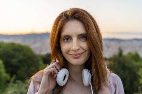 Junge rothaarige Frau mit Kopfhörern am Aussichtspunkt - AFVF03230