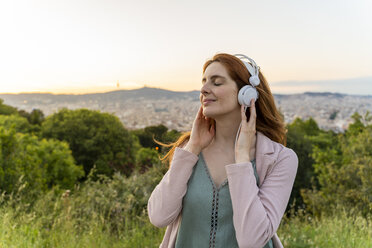 Junge rothaarige Frau mit Kopfhörern am Aussichtspunkt - AFVF03233