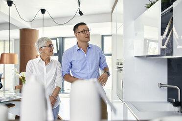 Man and mature woman talking in a kitchen retail store - ZEDF02429