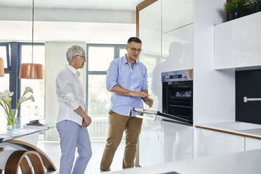 Man and mature woman talking in a kitchen retail store - ZEDF02432