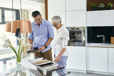 Man and mature woman in a kitchen retail store examining material samples - ZEDF02435