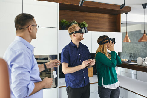 Paar mit VR-Brille beim Einkaufen für eine neue Küche im Ausstellungsraum - ZEDF02441